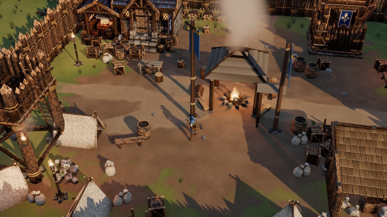 Inside the palisade at golden hour: the Hearth's fire burning under a timber shelter between two blue banners, a stone and timber forge glowing at the back, a watchtower and a tower flying the fleur-de-lis banner, canvas tents, crates, sacks and barrels around a trodden dirt yard, the player walking across it with a hammer.